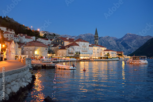 View of ancient picturesque city of Perast, Montenegro. Old medieval little town with red roofs and mountains on background of famous Kotor bay of Adriatic sea at blue hour. Travel and torism