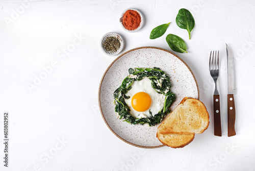 Fried eggs with fresh spinach and creamcheese on a plate om white background, top view, copy space photo