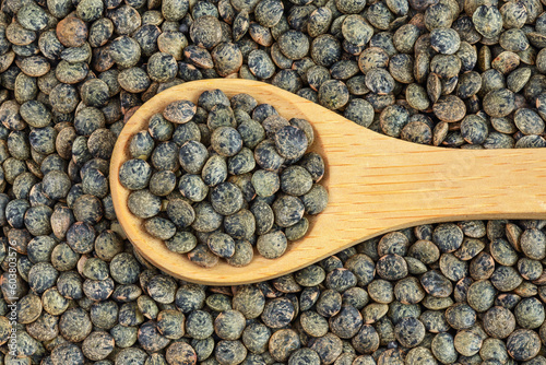 raw french green lentils in wooden spoon as a background. Top view. Flat lay photo