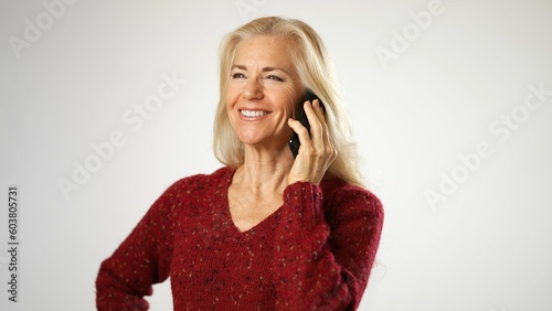 Happy middle aged woman relaxing, talking on smartphone with friends. Excited middle age lady chatting sharing news on mobile phone with grown up children