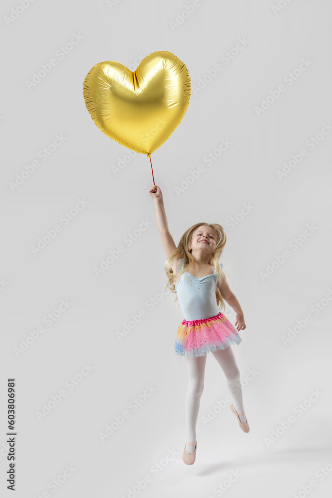 Studio portrait of adorable little girl holding large golden heart shaped balloon Studio portrait of adorable little girl holding large golden heart shaped balloon