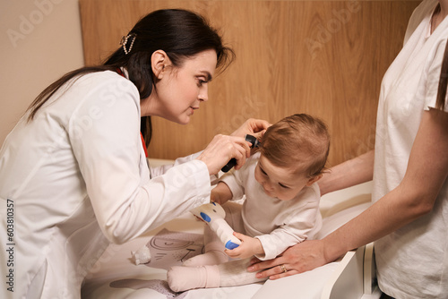Experienced otolaryngologist examining eardrum of little baby