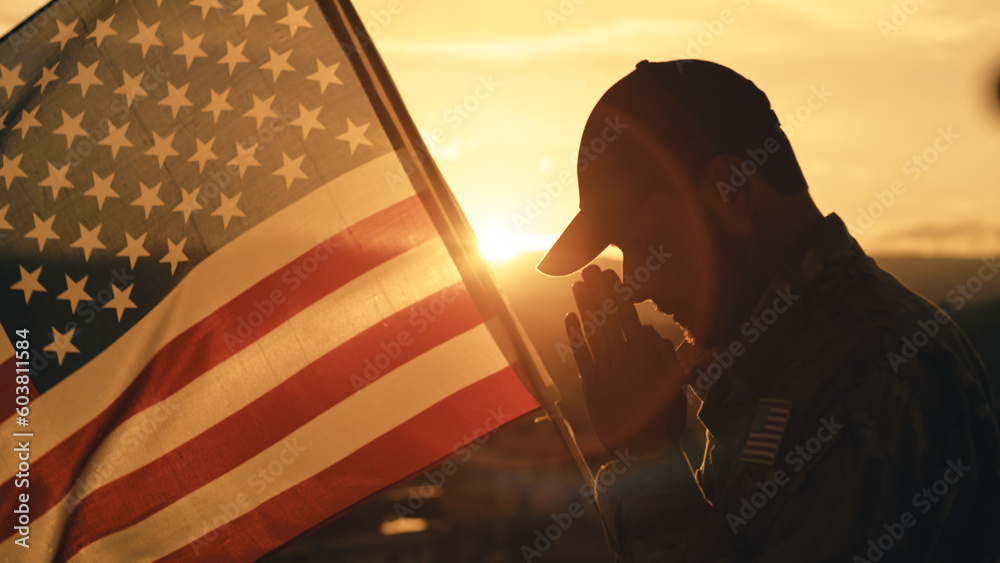 Silhouette of American soldier praying for memorial day against the flag outdoor - obrazy, fototapety, plakaty 