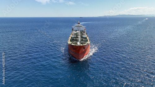 Aerial drone photo of huge crude oil tanker assisted by tug boat cruising open ocean deep blue sea