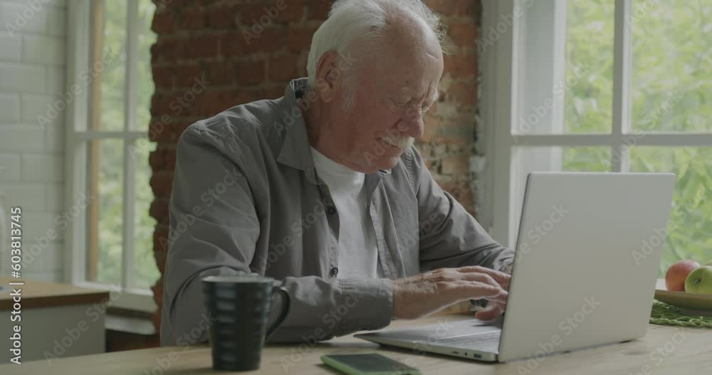 Senior businessman working with laptop typing concentrated on activity online indoors in apartment. Old age and remote job concept. Senior businessman working with laptop typing concentrated on activity online indoors in apartment. Old age and remote job concept.