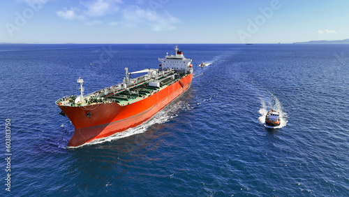 Aerial drone photo of huge crude oil tanker assisted by tug boat cruising open ocean deep blue sea