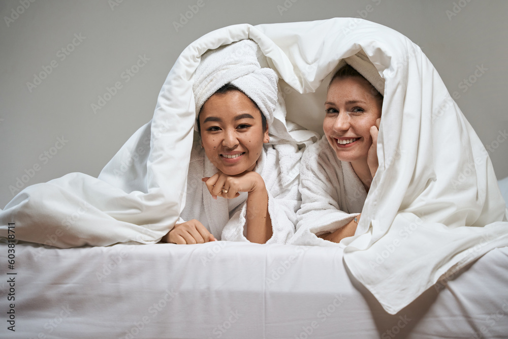 Photo of two girlfriends under a blanket in a hotel Photo of two girlfriends under a blanket in a hotel