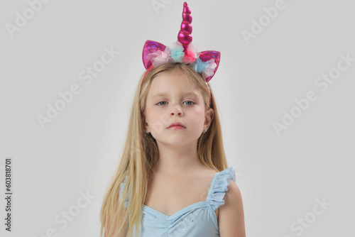 Studio portrait of beautiful bonde little girl wearing unicorn headband
 photo