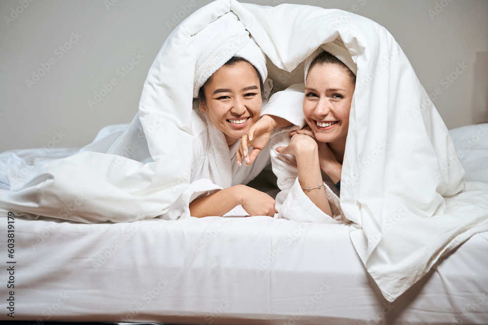 Two cheerful girlfriends smile sweetly from under the blanket Two cheerful girlfriends smile sweetly from under the blanket