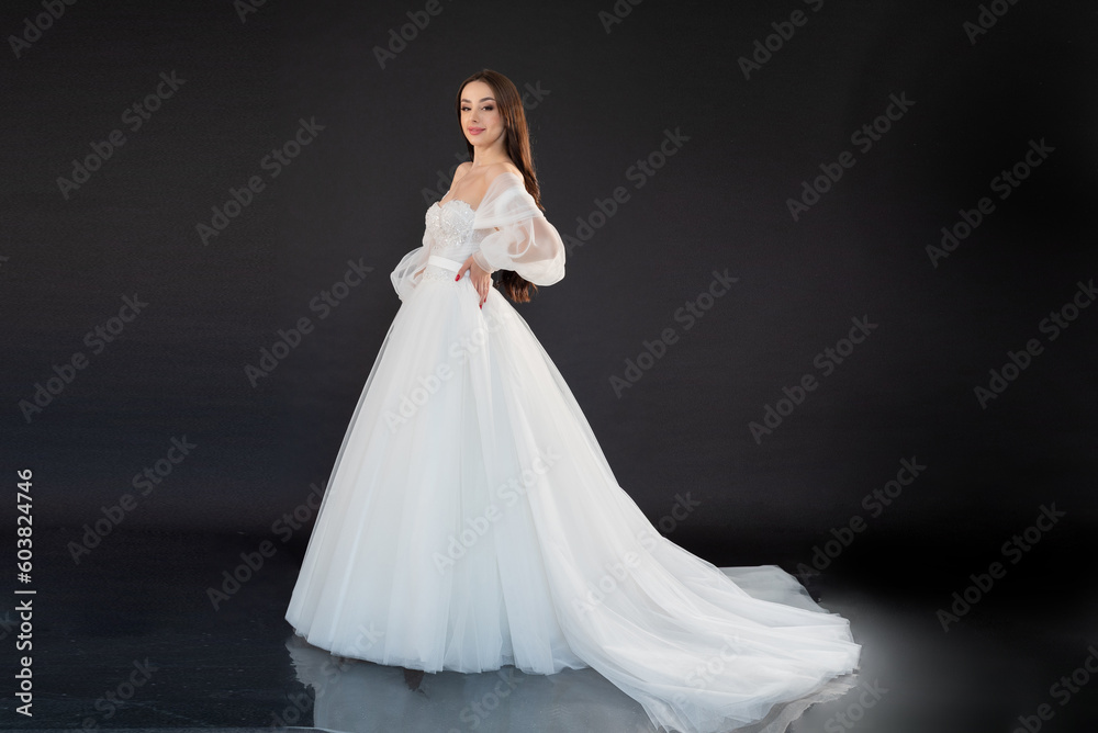 Beautiful fashion bride posing in wedding dress on black background Beautiful fashion bride posing in wedding dress on black background