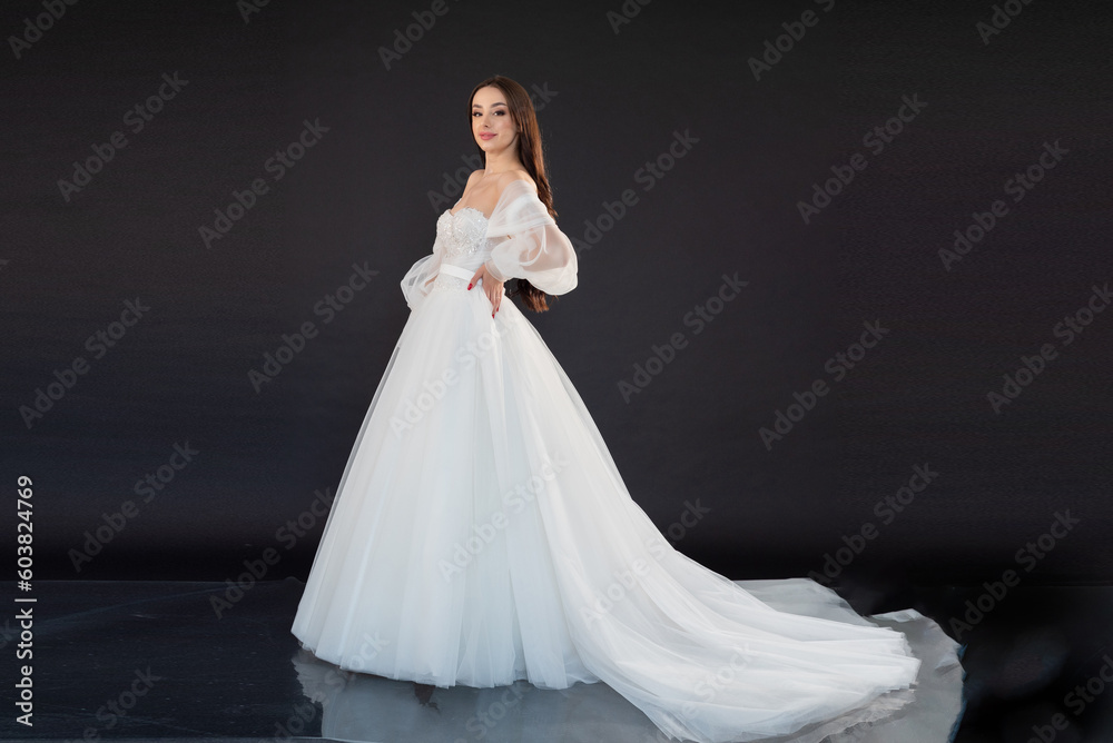  Beautiful fashion bride posing in wedding dress on black background 