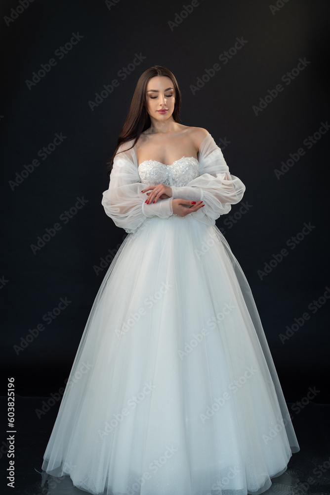Beautiful fashion bride posing in wedding dress on black background Beautiful fashion bride posing in wedding dress on black background