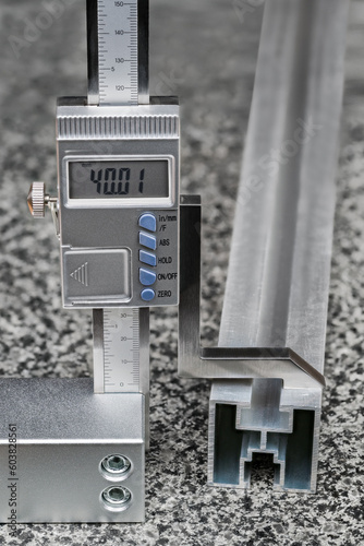 Accurate digital height gauge with metal scriber on plane granite measuring surface plate. Measurement of aluminum profile size. Marking out process to transferring dimensions by carbide drawing edge.