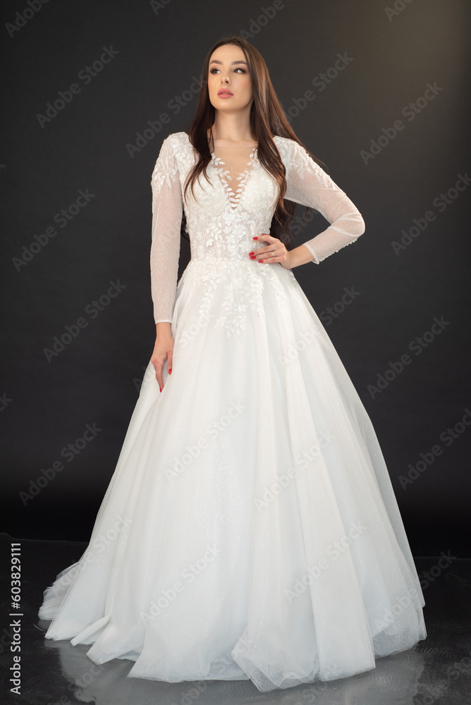 Beautiful fashion bride in wedding dress posing ob black background