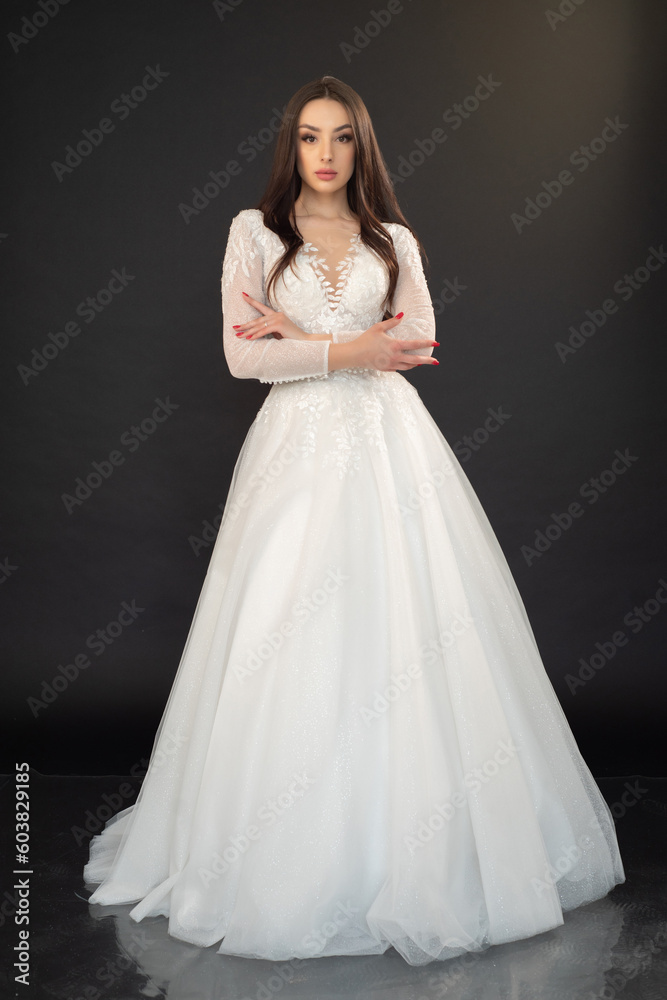 Beautiful fashion bride in wedding dress posing ob black background