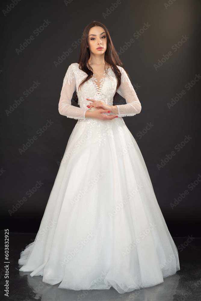  Beautiful fashion bride posing in wedding dress on black background 