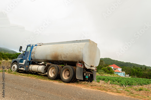 Water Truck Parked Beside A Tomato Garden At The Roadside