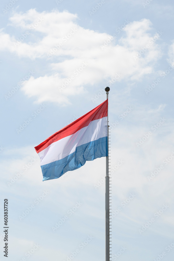 Flag of the Kingdom of Luxembourg - fluttering in the wind against a blue sky, natural photography