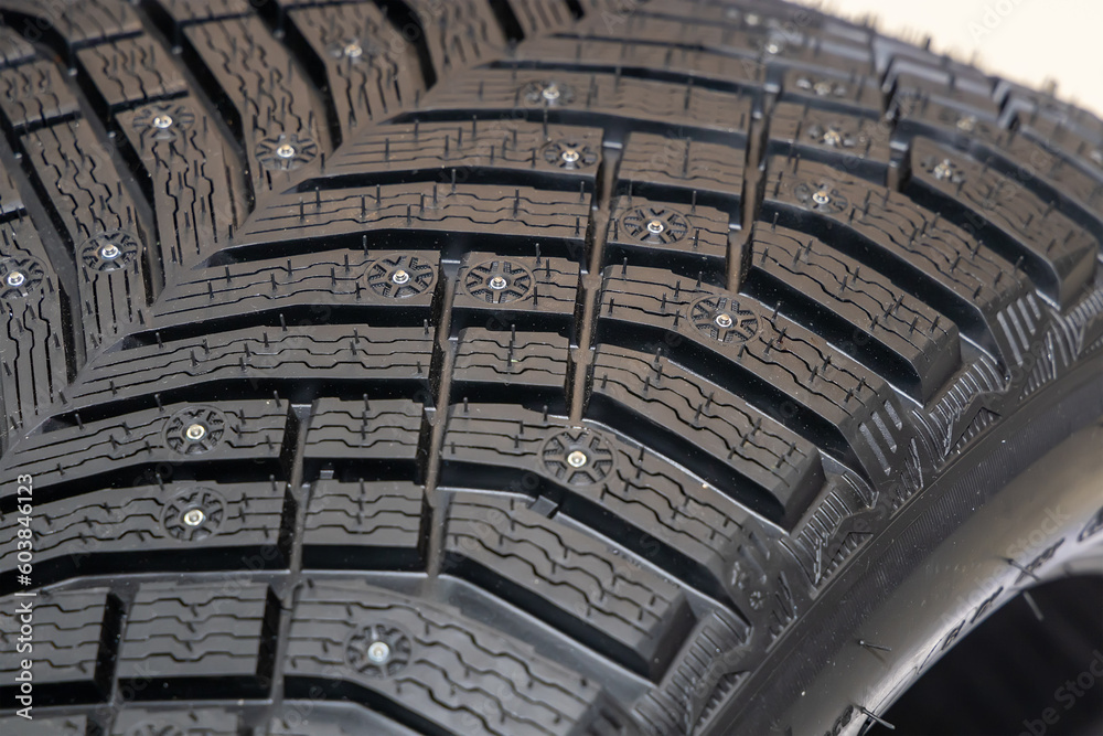 New tire with spikes and winter tread. Winter road safety. Winter wheel. Winter tire for passenger car