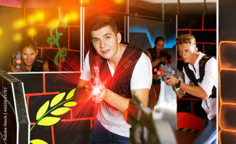 portrait of happy men and women playing emotionally laser tag game in arena
