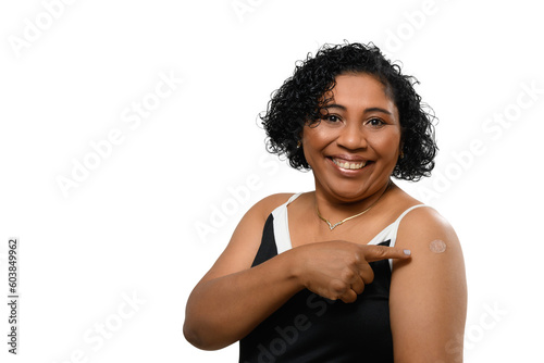 A woman smiles. She points to the vaccine sticker on her arm,