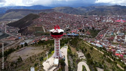 Aerial shot drone medium shot orbit to left around red tower on hill overlooking silver mining town on cloudy day photo