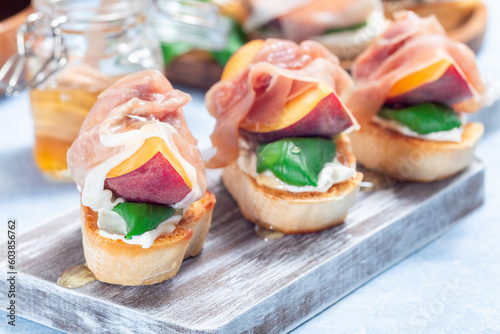 Prosciutto peach bruschetta, crostini with cream cheese, basil leaf, peach, prosciutto, horizontal