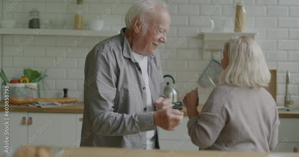 Slow motion of joyful senior couple dancing enjoying music in leisure time indoors at home. Modern lefestyle and happy retirement concept.