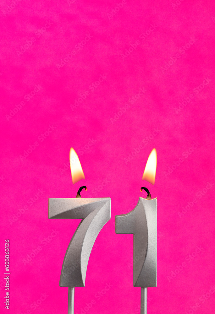 Candle 71 with flame - Silver anniversary candle on a fuchsia background Candle 71 with flame - Silver anniversary candle on a fuchsia background