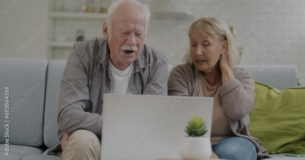 Grandmother and grandfather making online video call with laptop talking and gesturing at home. Internet communication and retired people concept. Grandmother and grandfather making online video call with laptop talking and gesturing at home. Internet communication and retired people concept.
