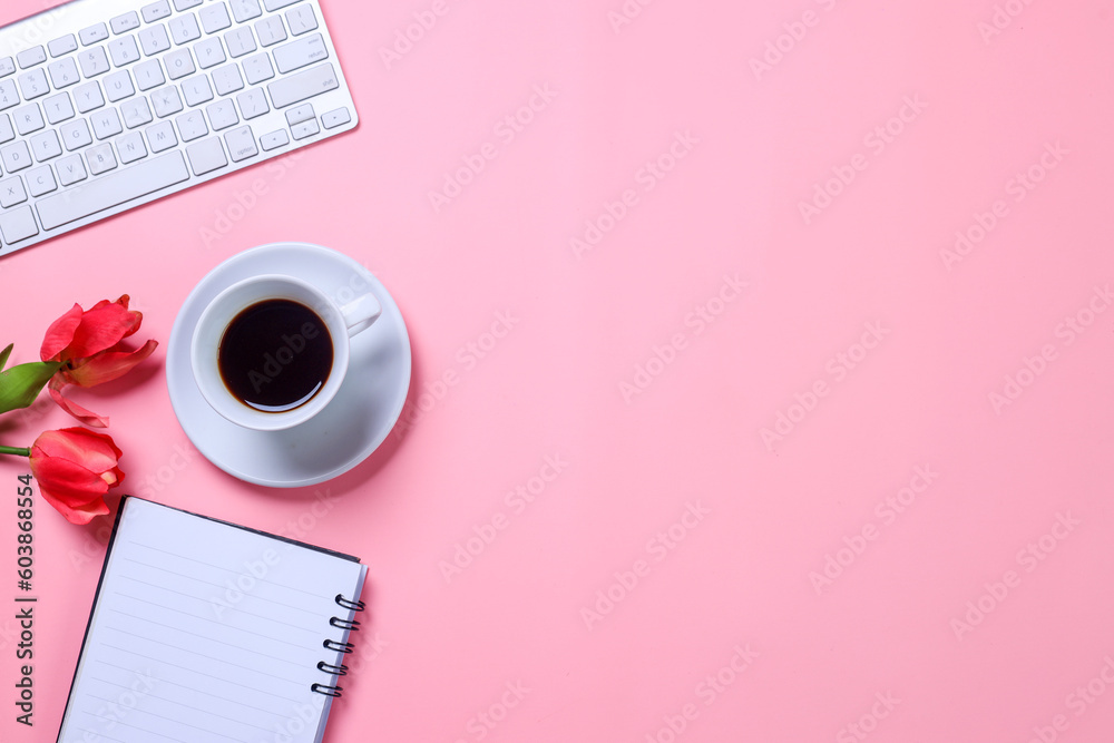 Styled stock photography pink office desk with keyboard, flowers, notebook and coffee cup. Top view with copy space. Flat lay.