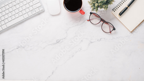 White office desk workplace with keyboard, mouse, notebook, eyeglass, pen and cup of coffee, Top view flat lay with copy space.