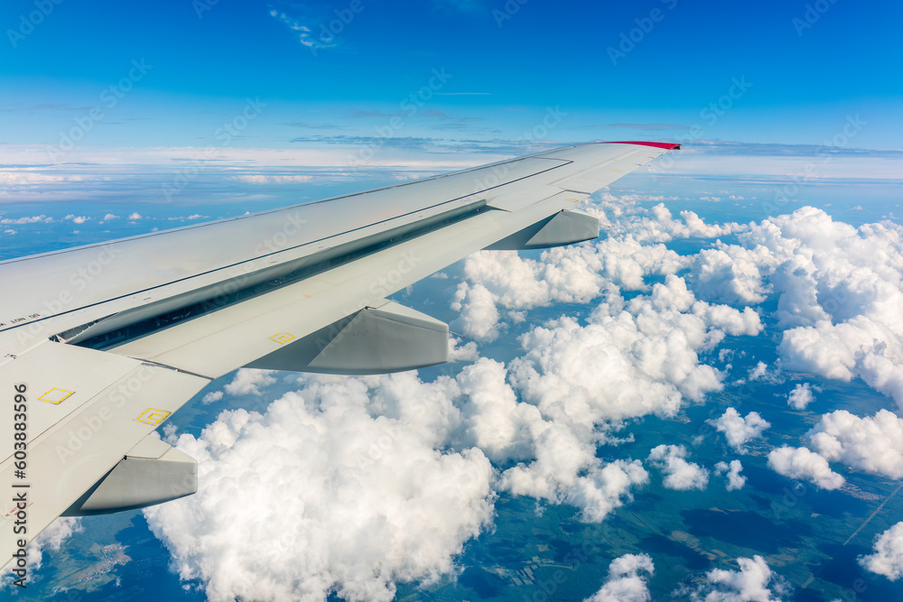 Fototapeta premium View from the airplane window at a beautiful cloudy sky and the airplane wing