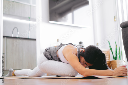 latin woman doing a gluteus pyramidal floor leg stretching at home on a yoga mat