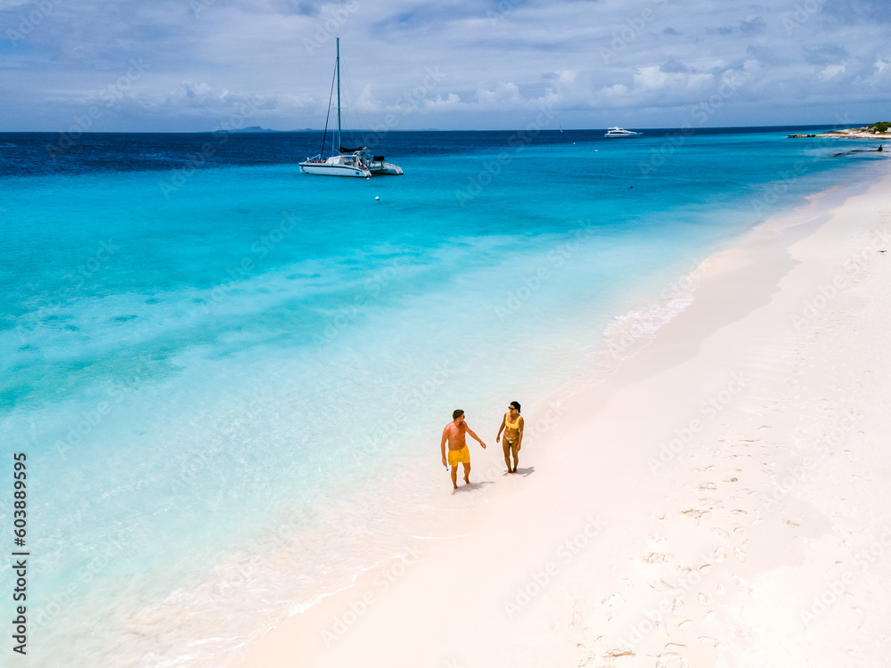a couple of men and women on a boat trip to Small Curacao Island with a white beach and turqouse colored ocean on a sunny day