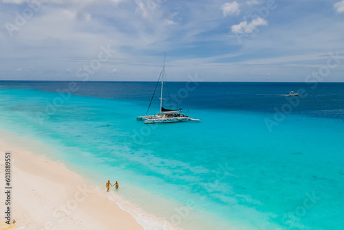 a couple of men and women on a boat trip to Small Curacao Island with a white beach and turqouse colored ocean on a sunny day