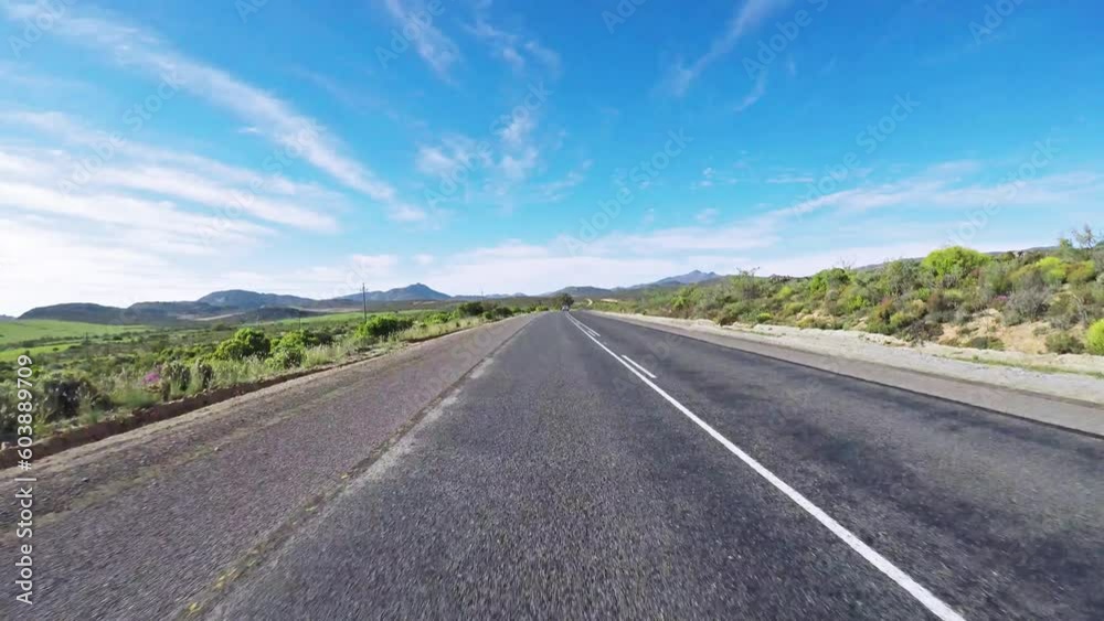 Time lapse, road trip and travel speed of a car while driving and traveling on a country road. View of adventure, transport and a scenic drive on asphalt paving through nature below a blue sky Time lapse, road trip and travel speed of a car while driving and traveling on a country road. View of adventure, transport and a scenic drive on asphalt paving through nature below a blue sky