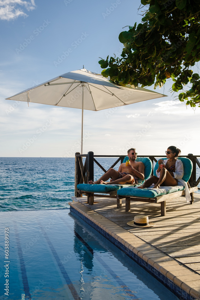 Curacao, couple man and woman mid age relaxing by the swimming pool during a vacation in the Caribbean