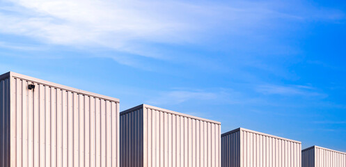Panoramic view of industrial corrugated metal Warehouse Buildings group against blue Sky in perspective side view