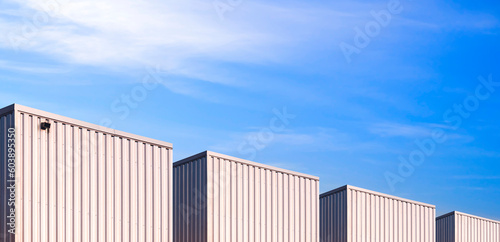 Panoramic view of industrial corrugated metal Warehouse Buildings group against blue Sky in perspective side view