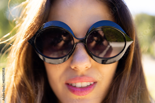 Portrait close up of smiling fit caucasian woman wearing sunglasses in sunny garden