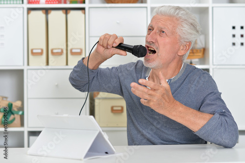 Senior old nice man singing into microphone