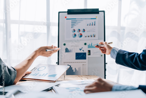portrait of young asian business team presents business profits to colleagues at meeting, explaining business turn over on flipchart to coworkers in office with using tablet.
