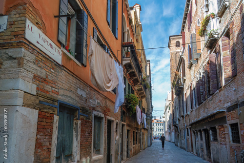 A narrow street of Venice with a male silhouette in the distance. The Center of Tourism and Travel in Europe. © Maria