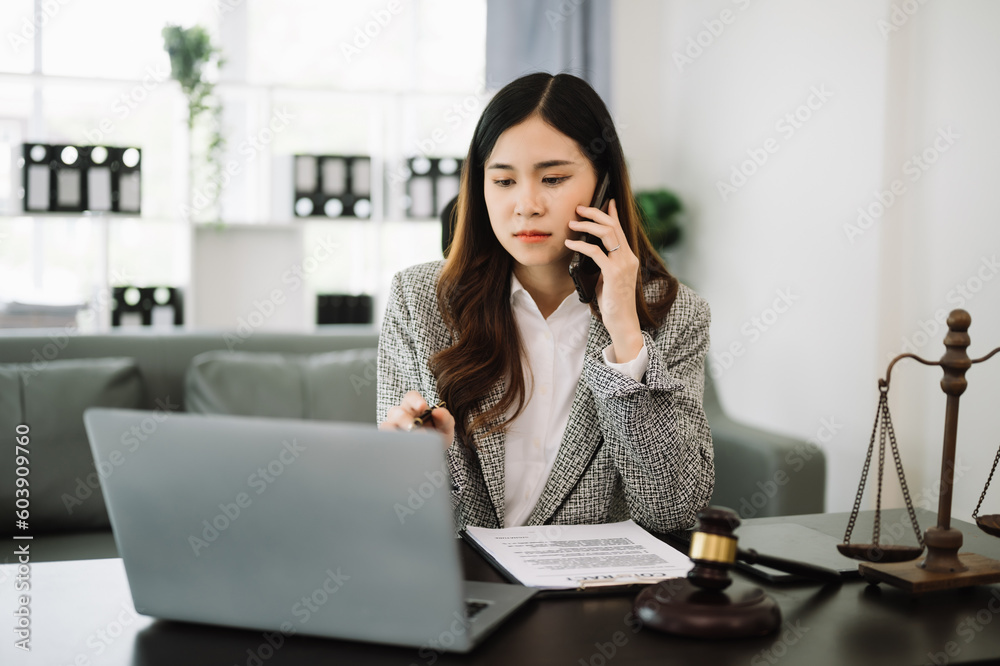 Asian lawyer woman working with a laptop and tablet in a law office. Legal and legal service concept. Looking at camera Asian lawyer woman working with a laptop and tablet in a law office. Legal and legal service concept. Looking at camera