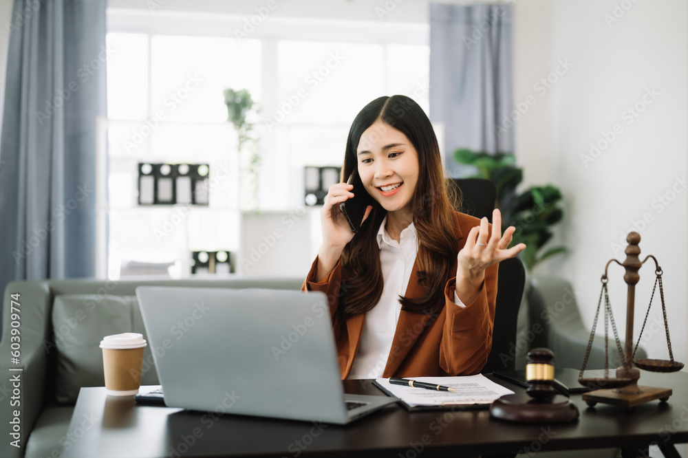 Asian female lawyer chatting online with client on laptop, smartphone discussing details of lawsuit. in modern office Asian female lawyer chatting online with client on laptop, smartphone discussing details of lawsuit. in modern office