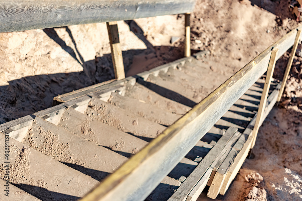 Descent into a deep pit during the construction of the building. Safety in construction. Ladder for descending to reinforced concrete foundations. Ladder to success. Wooden ladder for workers. Descent into a deep pit during the construction of the building. Safety in construction. Ladder for descending to reinforced concrete foundations. Ladder to success. Wooden ladder for workers.