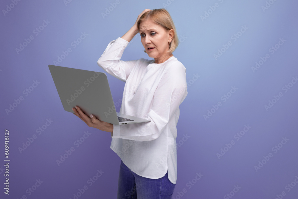 mature woman with blond hair works remotely using laptop mature woman with blond hair works remotely using laptop