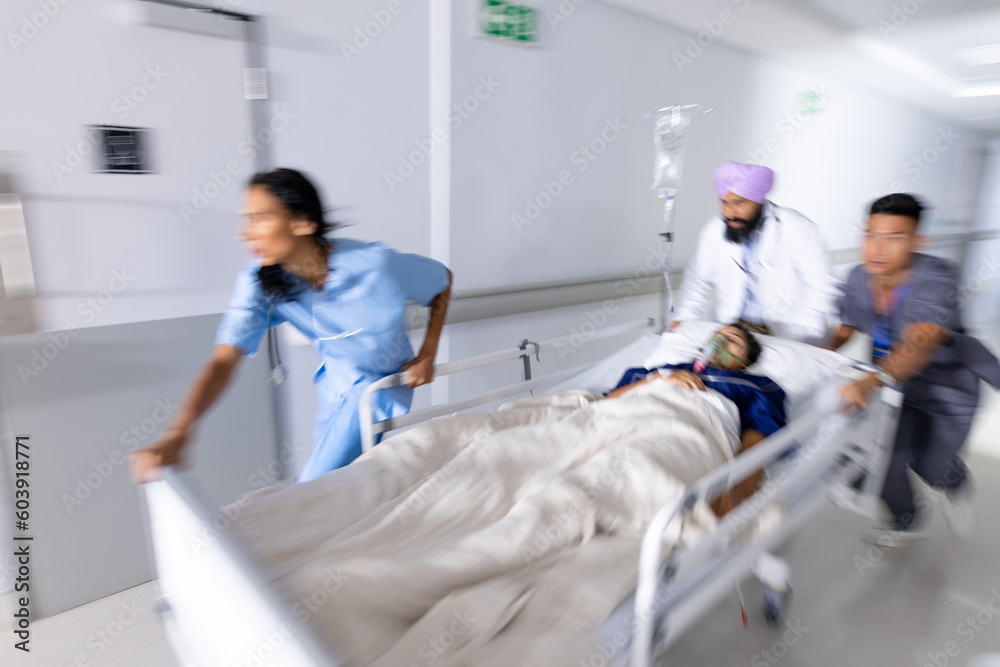 Diverse doctors urgently pushing patient lying in bed in corridor at hospital Diverse doctors urgently pushing patient lying in bed in corridor at hospital