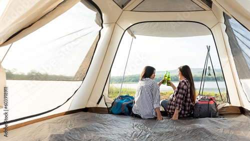 Fotografiet Asian LGBTQ+ couples drinking drinks in a romantic atmosphere inside a camping tent, LGBTQ couples watching nature, rivers, forests, camping atmosphere